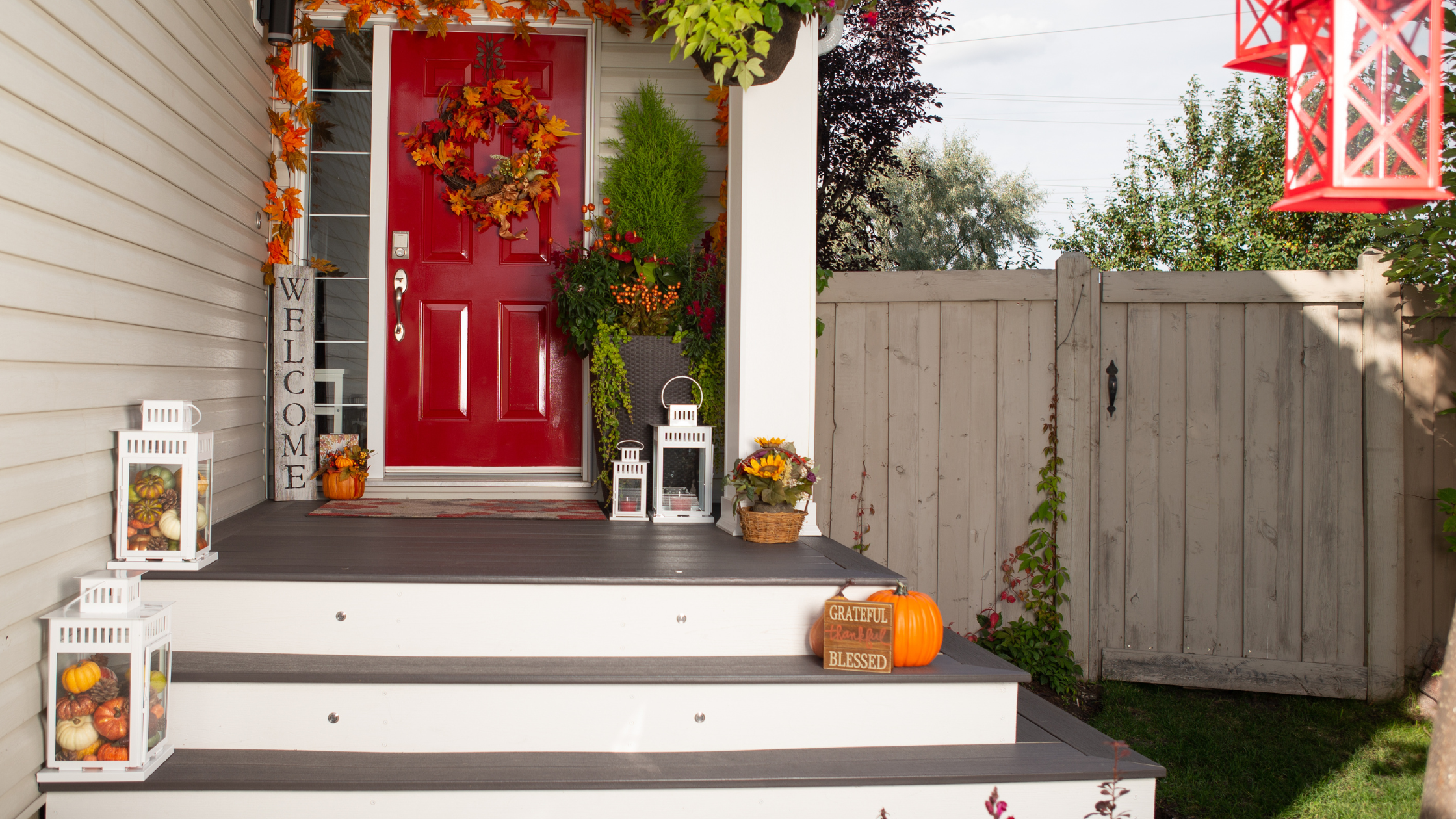 A white home's front stoop, with a red door and fall decorations